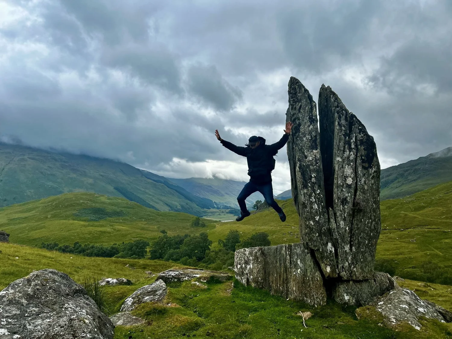A traveller leaping between standing stones in a Highland glen