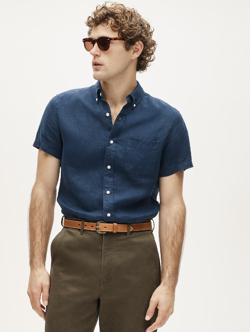 A close-up shot of a man wearing a dark navy blue short-sleeve J.Crew linen-cotton blend shirt, paired with olive brown trousers and a tan leather belt.