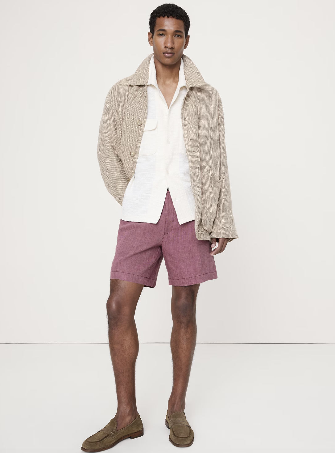 A man wearing dusty rose 7-inch linen pull-on shorts from Banana Republic, styled with brown suede loafers and a light beige shirt.