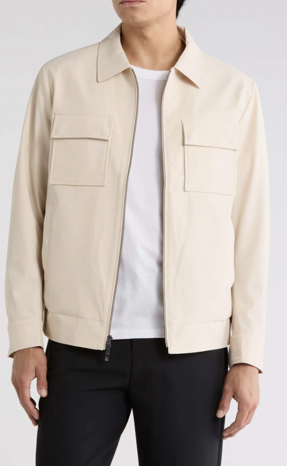 Man wearing the Robert Barakett Jerry Utility Jacket in cream with chest flap pockets over a white tee and black trousers.