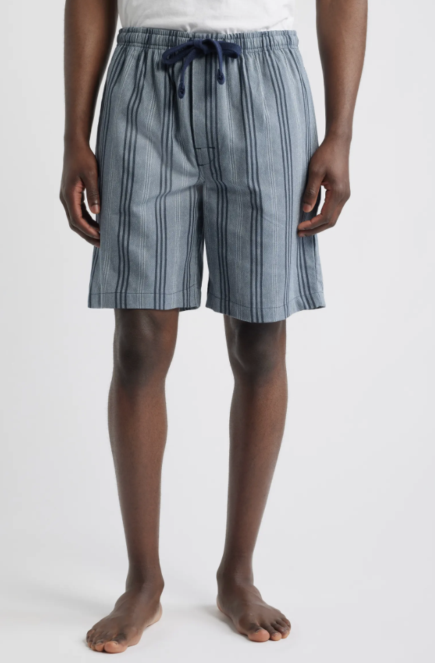 A man wearing khaki J.Crew Tech shorts paired with off-white canvas sneakers, showcasing a clean and functional casual summer outfit.