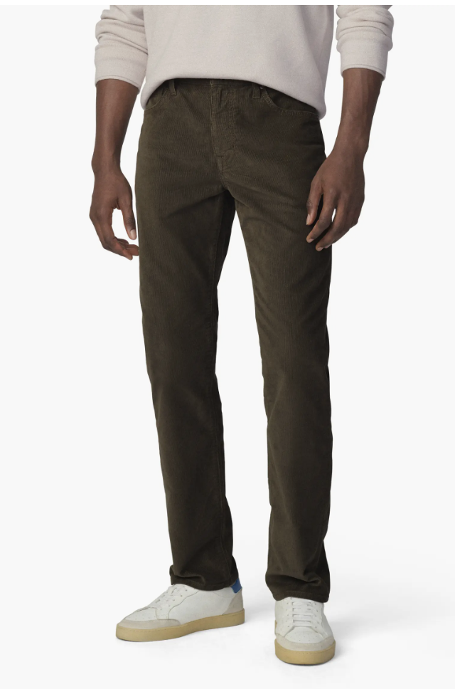Man wearing Joe's Brixton Slim Straight-Leg Corduroy Jeans in dark olive with a light grey sweater.