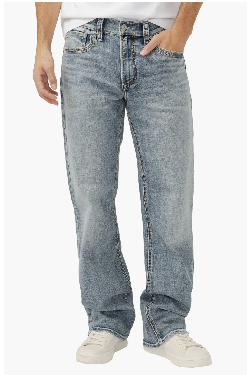 Man wearing a white TravisMathew Cloud Crewneck T-shirt tucked into dark wash denim jeans for a casual spring outfit.