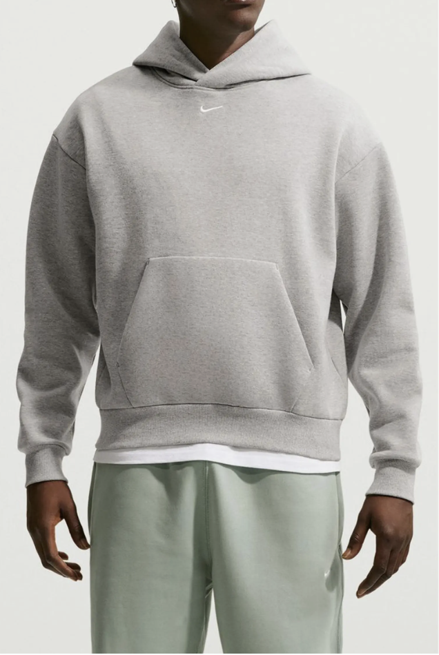 Man wearing the Nike Solo Logo Fleece Hoodie in heather grey with a small white swoosh at the chest.