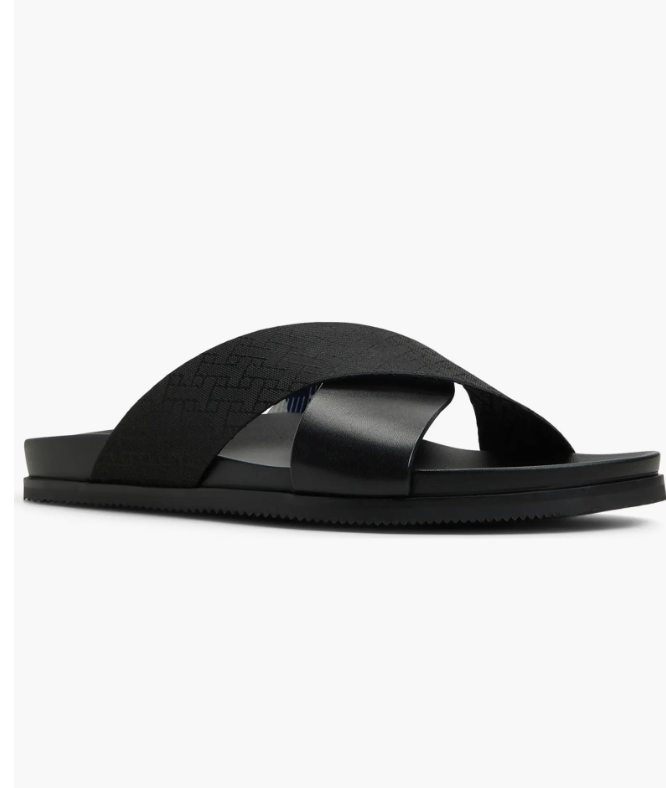 A pair of Ted Baker London Saltburn leather slide sandals in black, featuring a crisscross strap design and cushioned footbed for elevated summer style.
