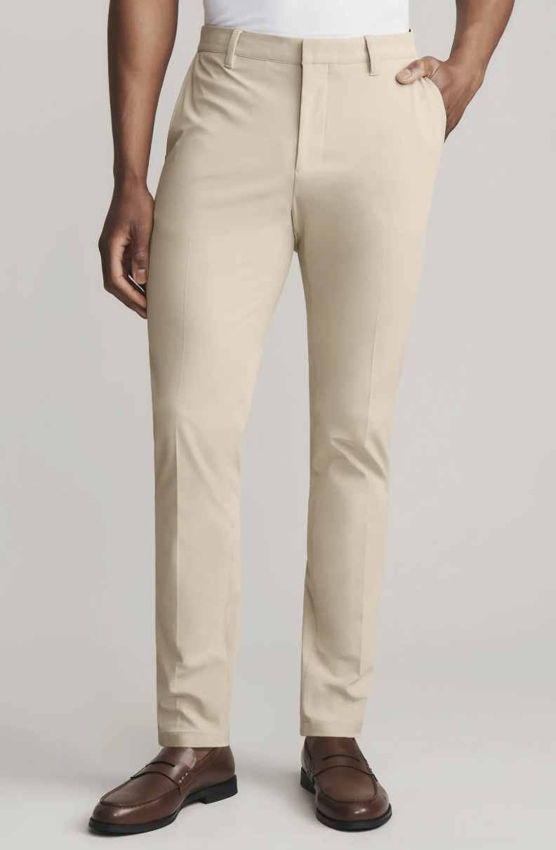 Man wearing khaki-colored Rhone Commuter Pro Slim Fit Pants with dark brown loafers.