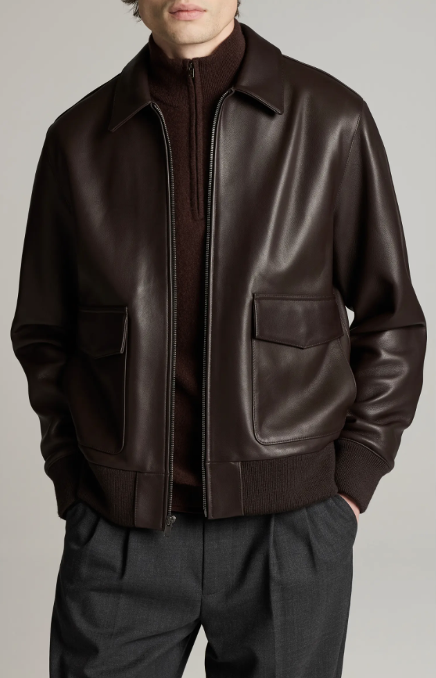Man wearing a dark brown aviator leather bomber jacket over a burgundy quarter-zip sweater.