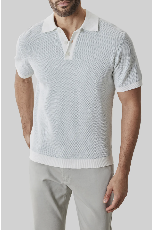 A man wearing a light blue, short-sleeve knit polo shirt paired with light gray chinos, styled for a modern 2026 summer look.