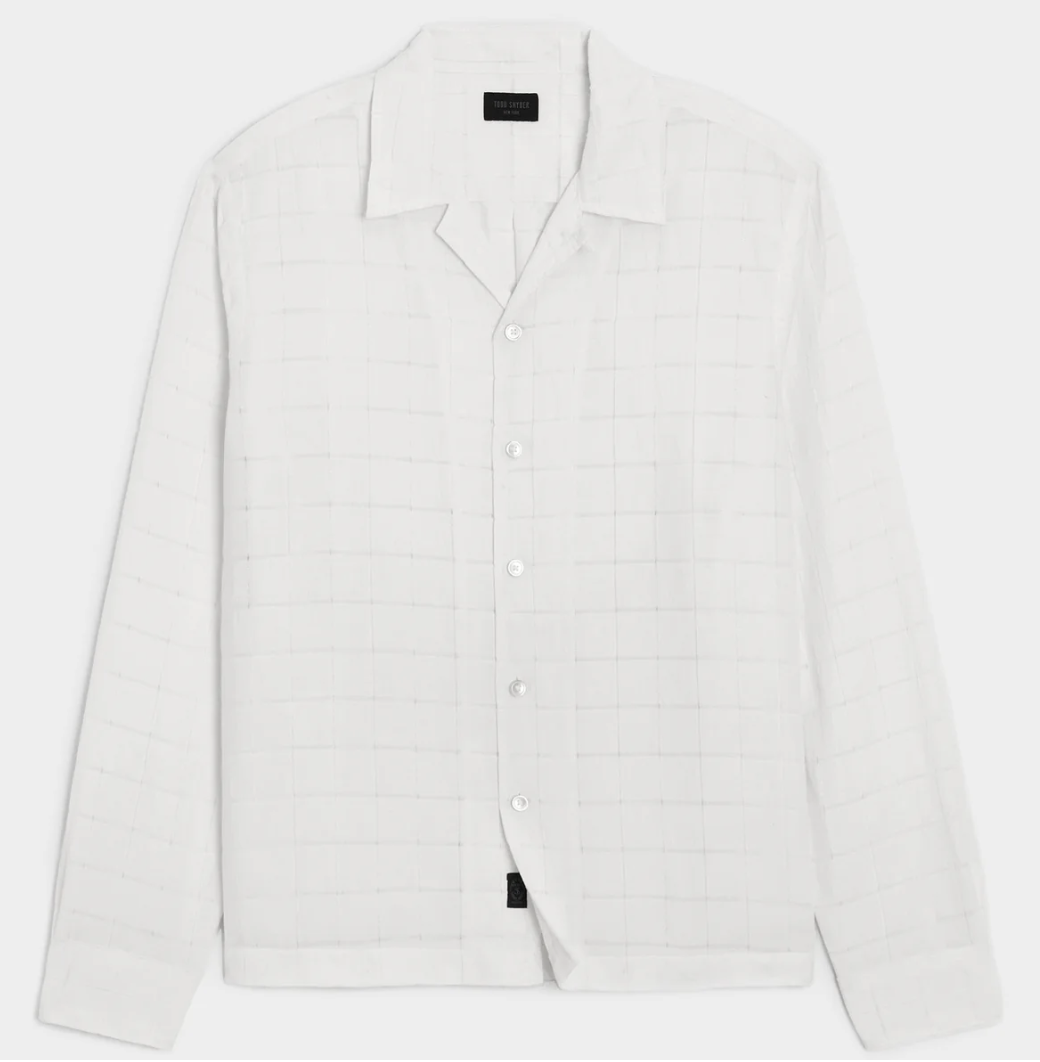 A close-up shot of a white Todd Snyder Italian Linen camp collar shirt, showcasing its subtle grid-textured weave pattern and relaxed open collar.