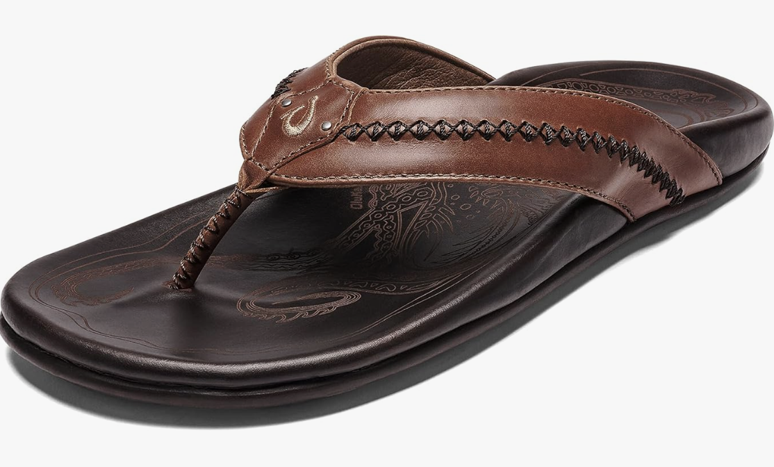 A pair of dark brown OluKai Nui premium leather sandals for men, featuring a hand-sewn toe post and an anatomical footbed for arch support.