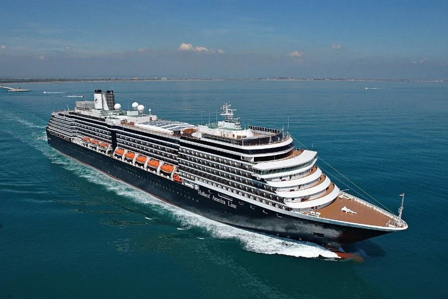 A large cruise ship sailing in open water with a clear blue sky overhead.