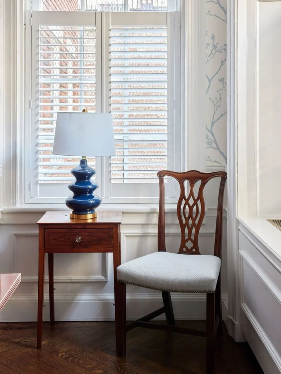 This little seating nook at the Astor House in NYC proves how much impact thoughtful details can have. A tailored seat cushion in @thibaut_1886 fabric complements patterned wallpaper from @schumacher1889 , and a playful blue lamp adds just the right 
