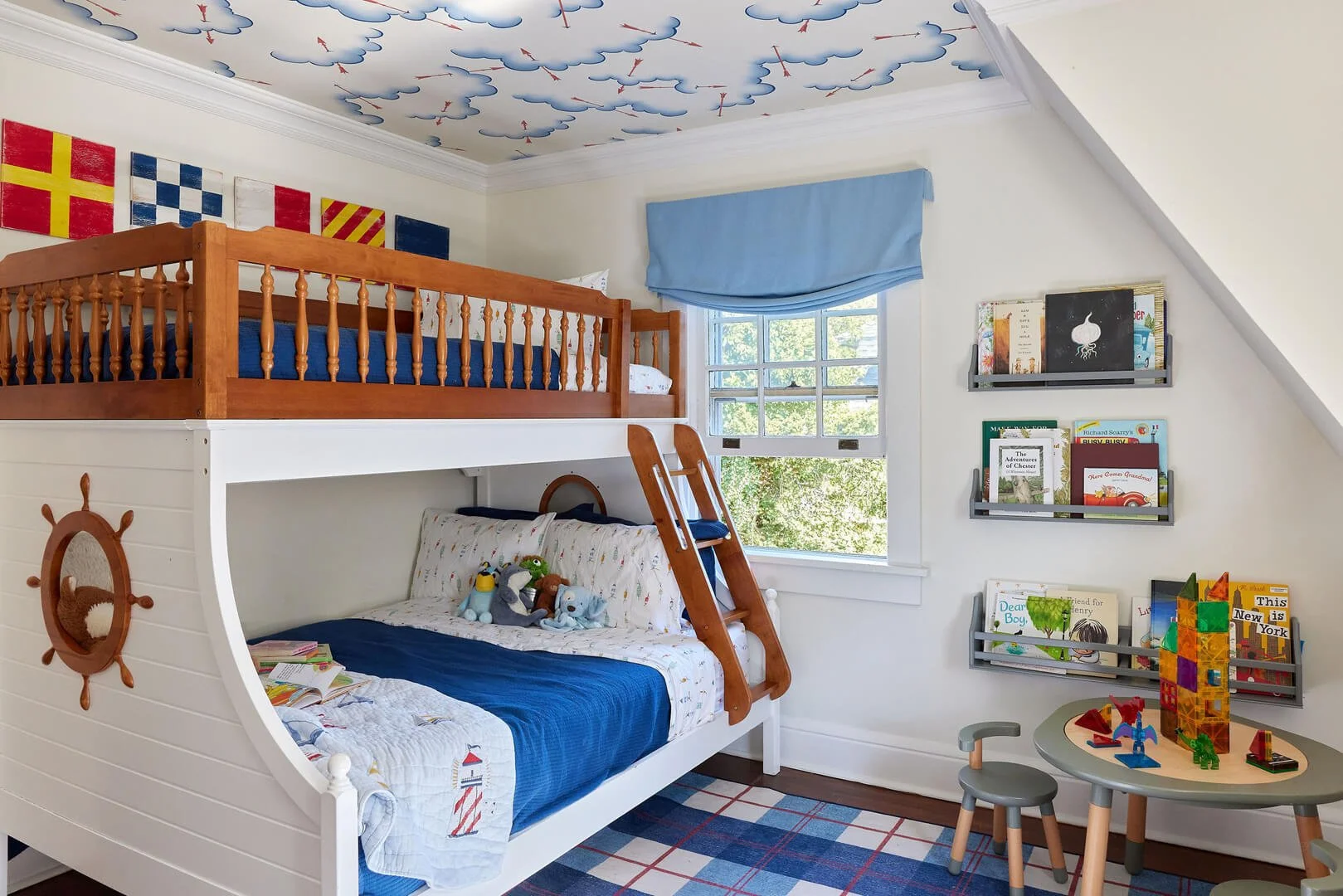Custom kids room interior design by Style and Space Interiors with fun wallpaper on the ceiling and a nautical theme