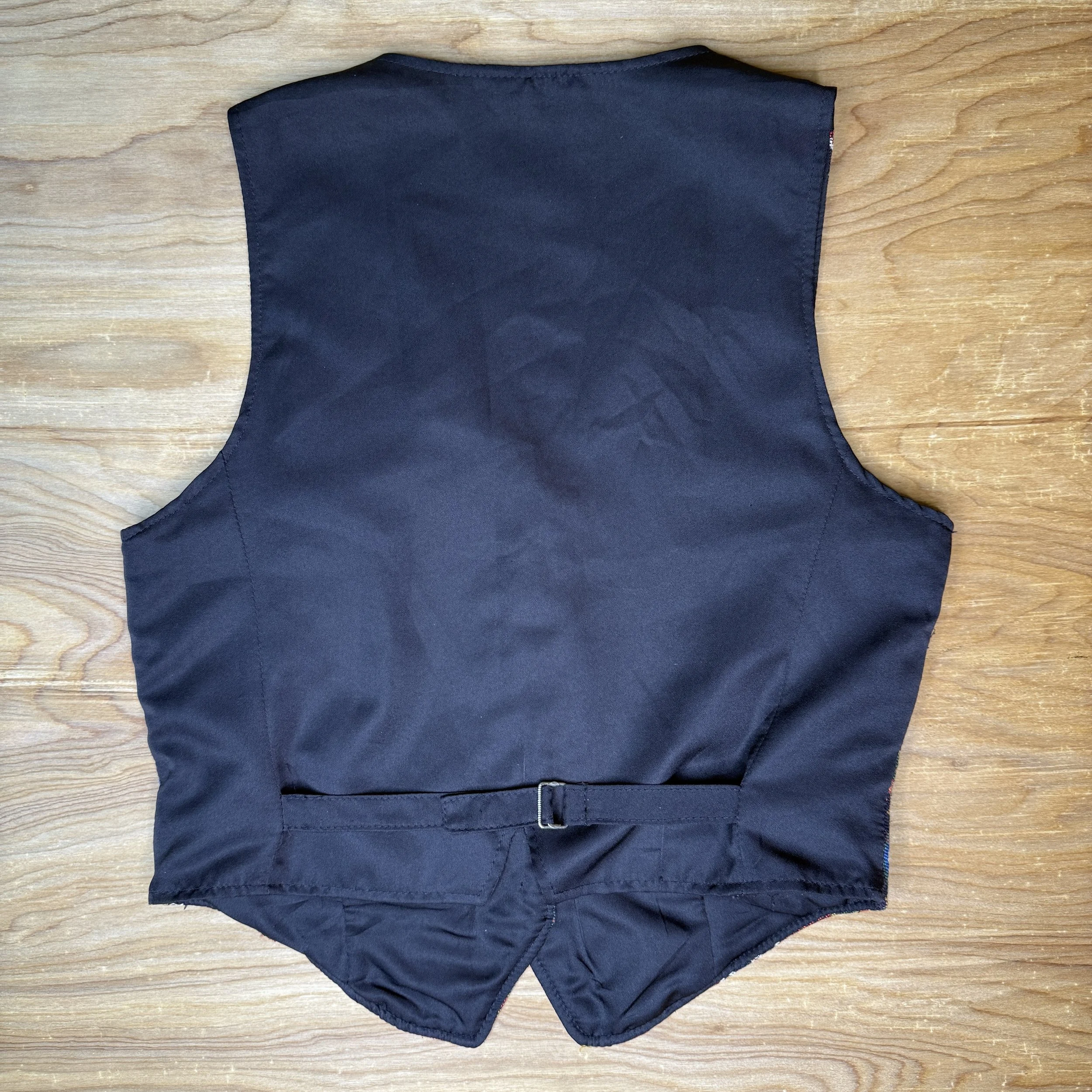 Back view of vest showing solid black satin and adjustable buckle strap