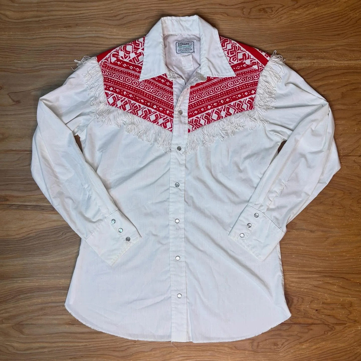 A classic pearl snap, but make it West Coast Country 🤠

This vintage H Bar C California Ranchwear western shirt is loud in all the right ways - crisp white cotton, bright red bandana-print yoke, and a full fringe curtain that sways with every step. 