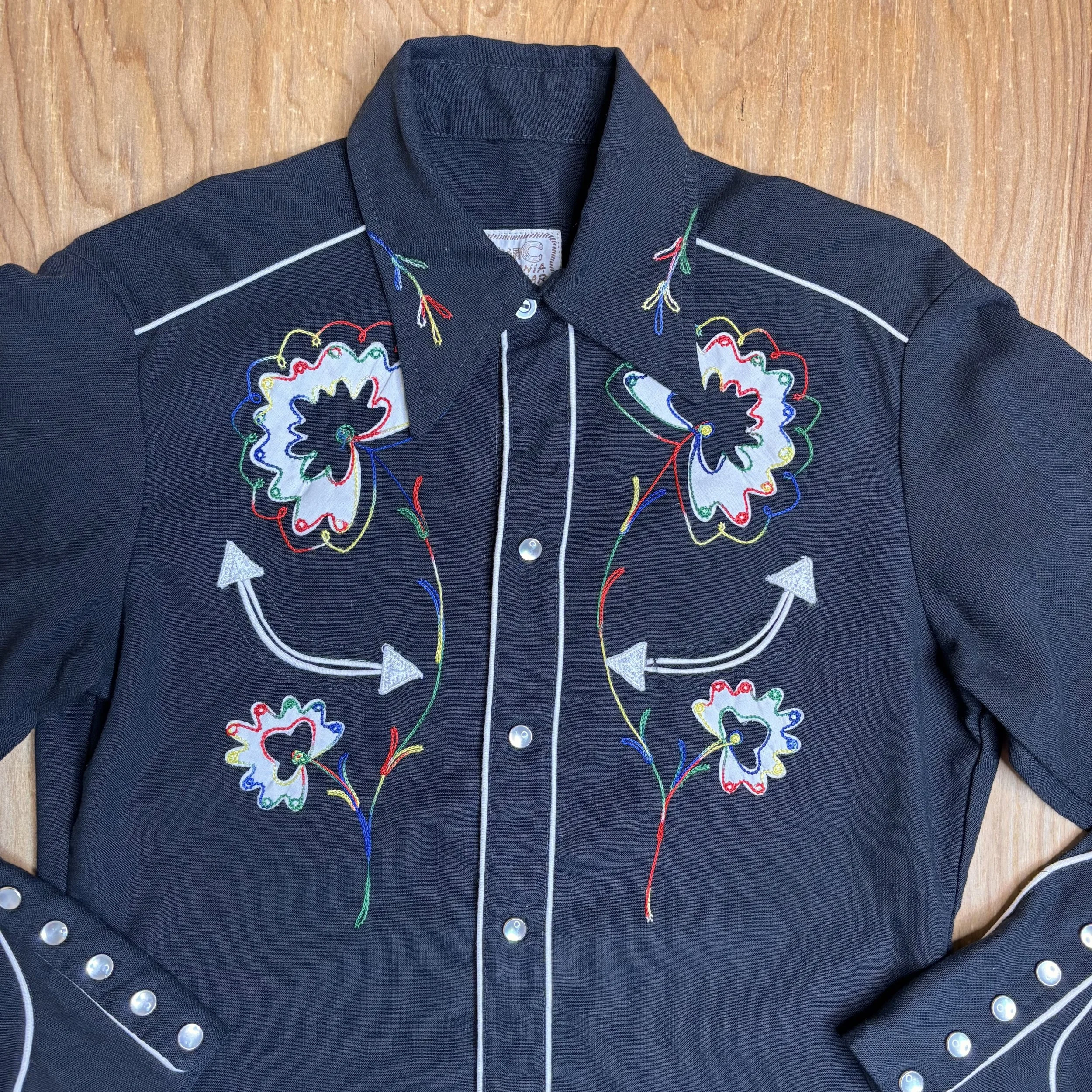 Close-up of floral embroidery detail and pearl snap buttons on H Bar C vintage western shirt.