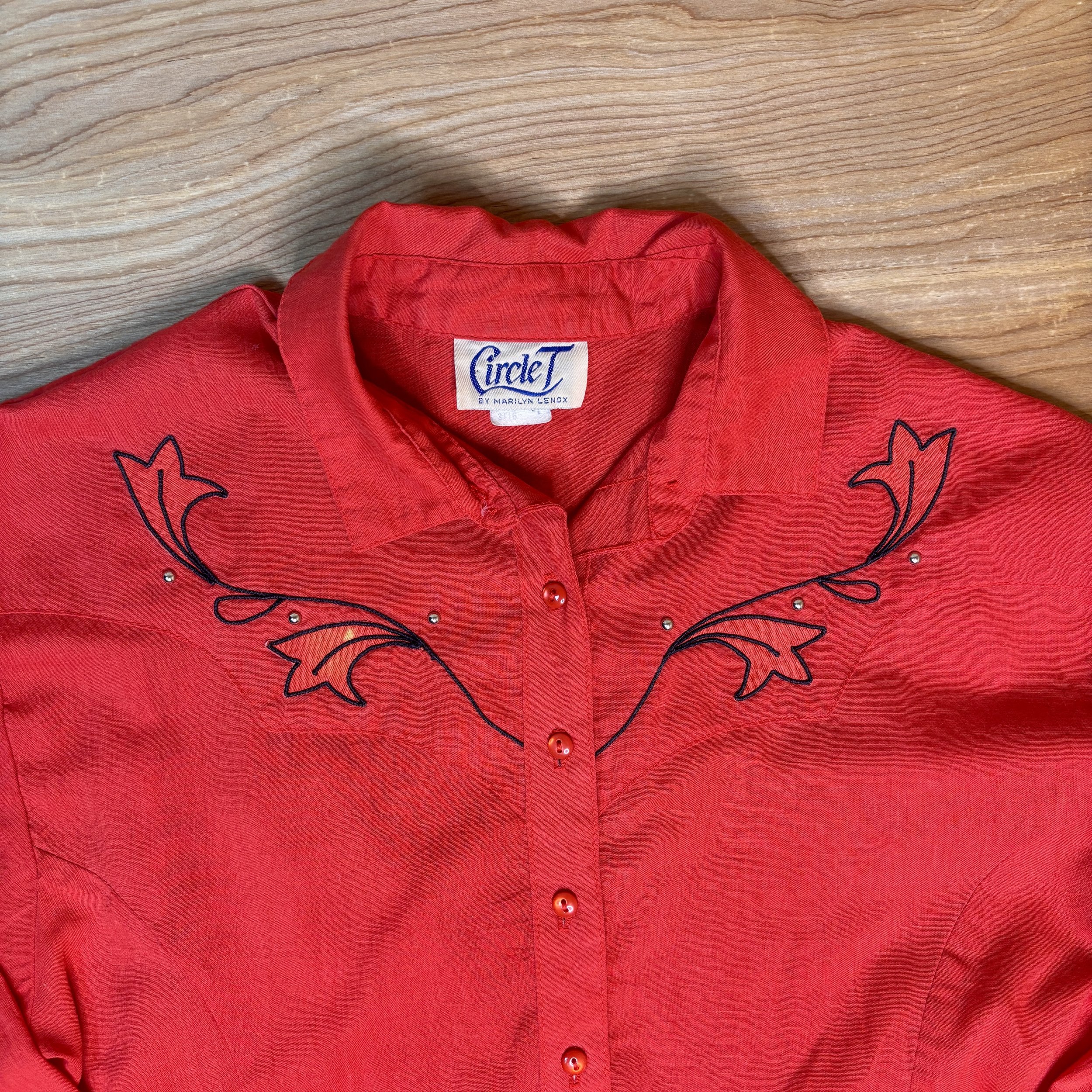 Close-up of collar and Circle T by Marilyn Lenox label on red shirt