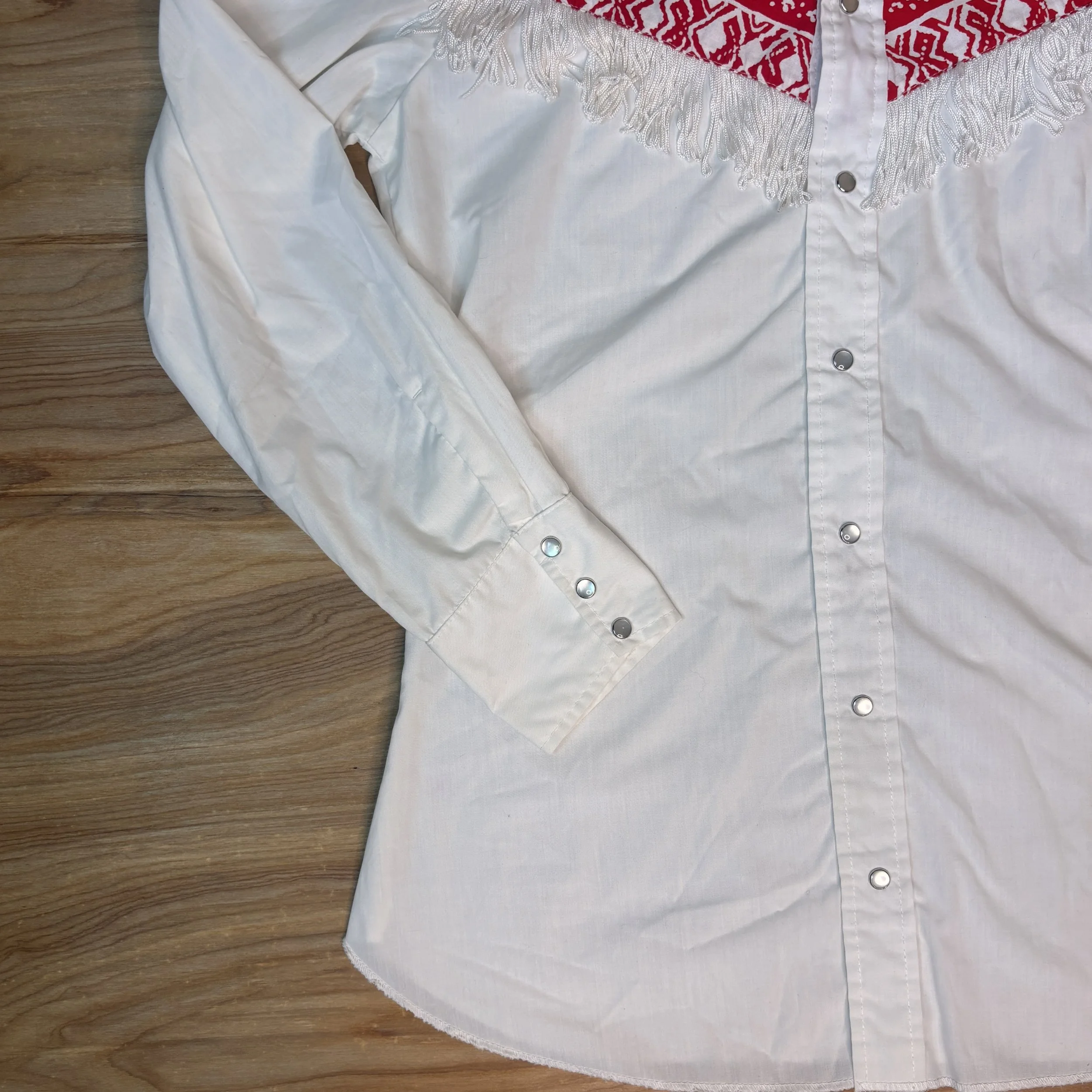 Close-up of white sleeve and pearl snap cuff on vintage western fringe shirt.