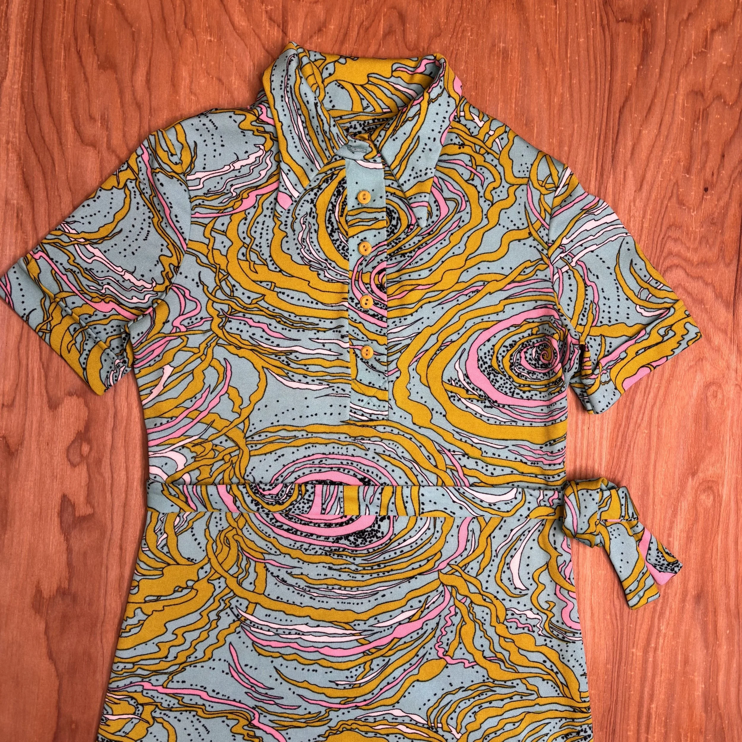Close-up of vibrant psychedelic print fabric in lime green, pink, turquoise, black, and white on 1960s dress.
