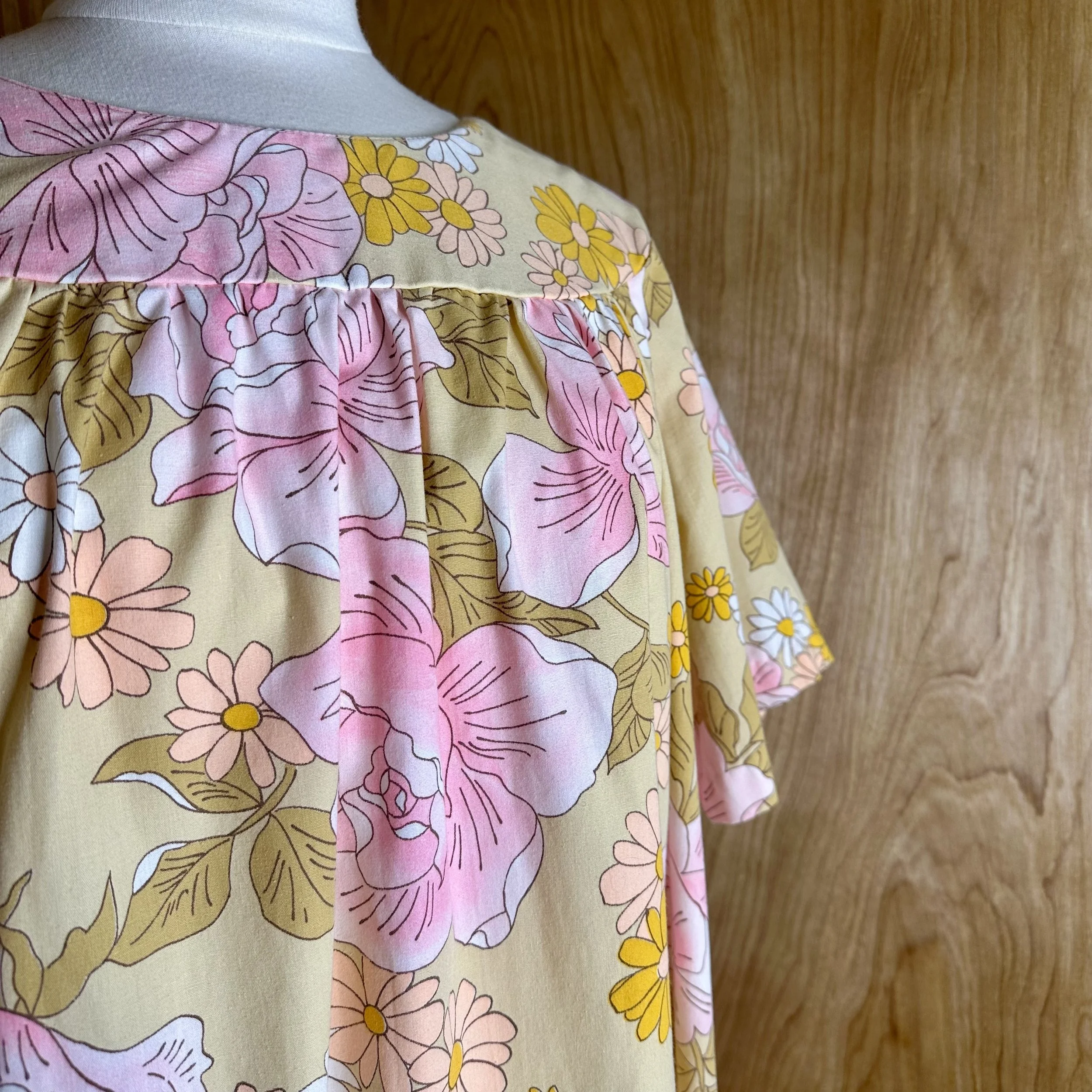 Close-up of retro 1970s floral fabric featuring pink roses, daisies, and green leaves.