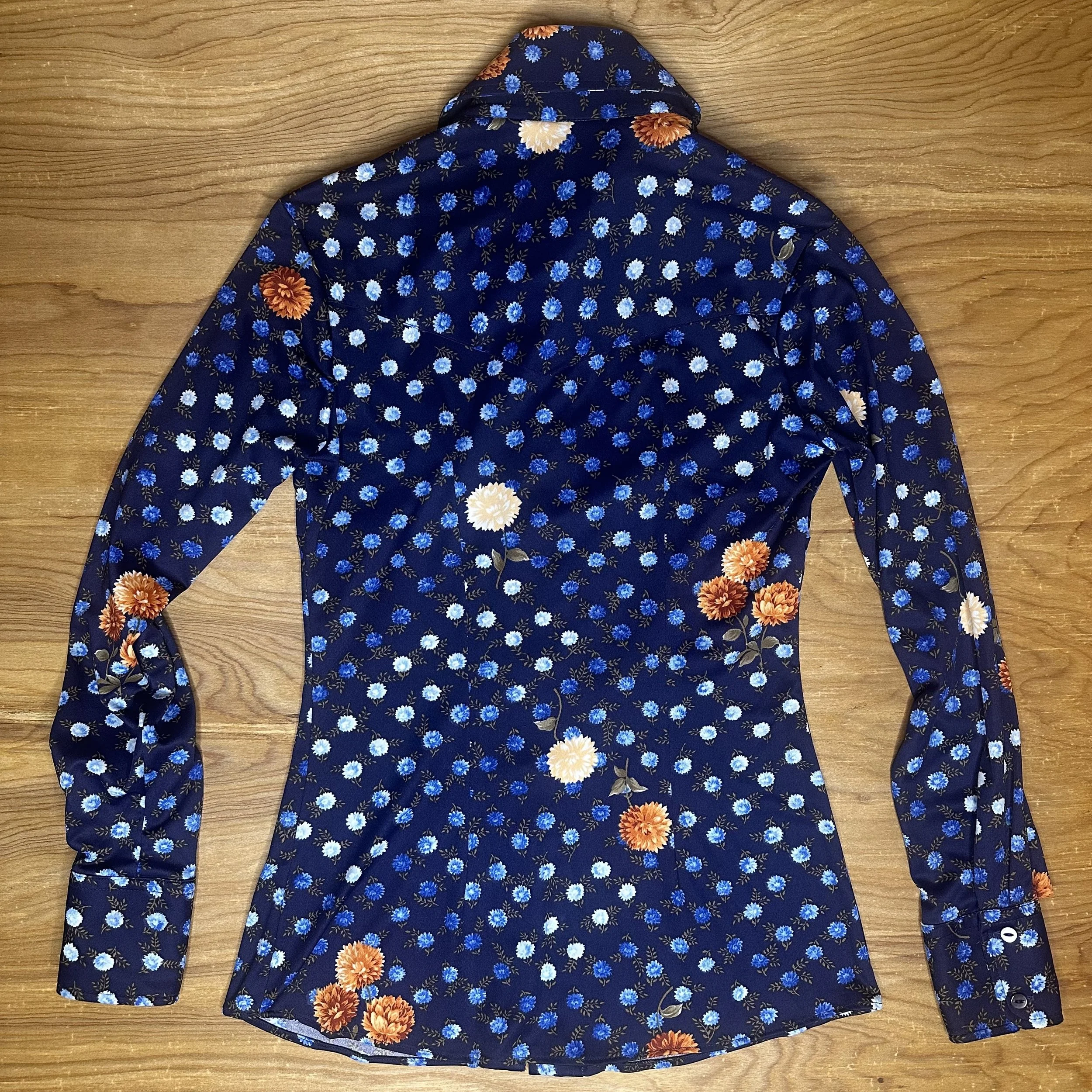 Full view of back of vintage Miller Western Wear navy satin pearl snap shirt with bright floral print.