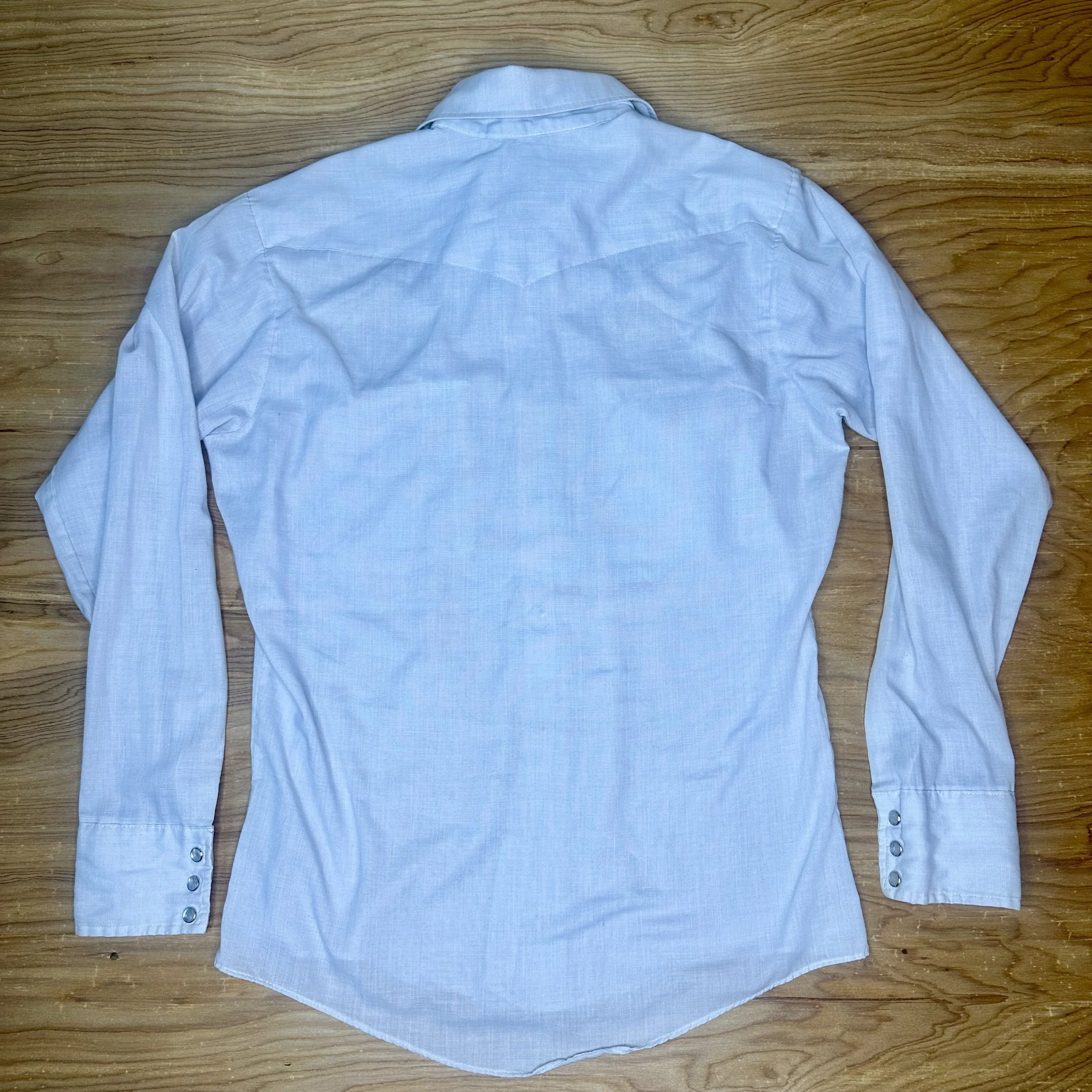 Back view of vintage light gray Bronco pearl snap western shirt showing clean yoke and curved hem.