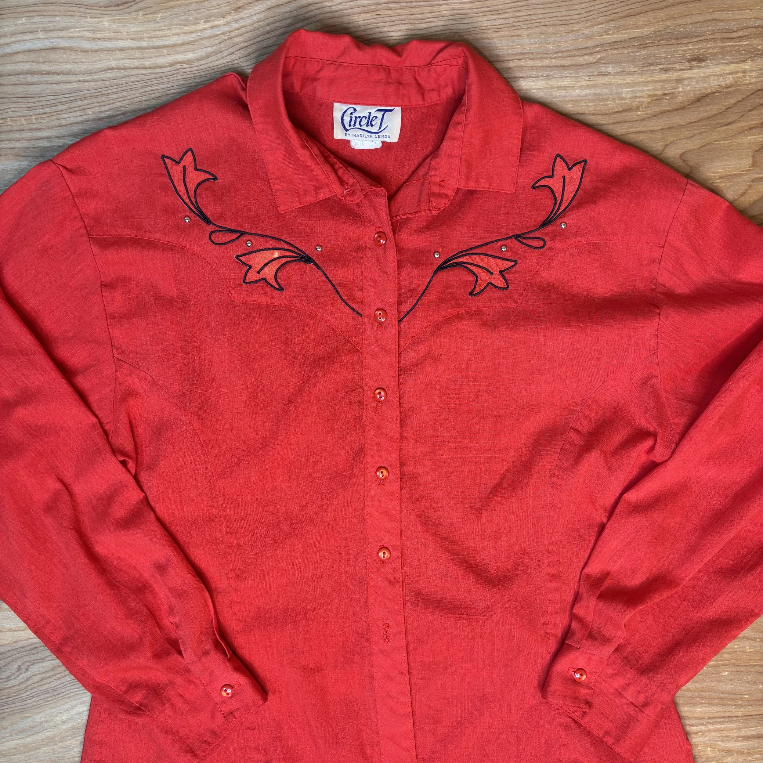 Detailed view of embroidered yoke design with rhinestones on red fabric