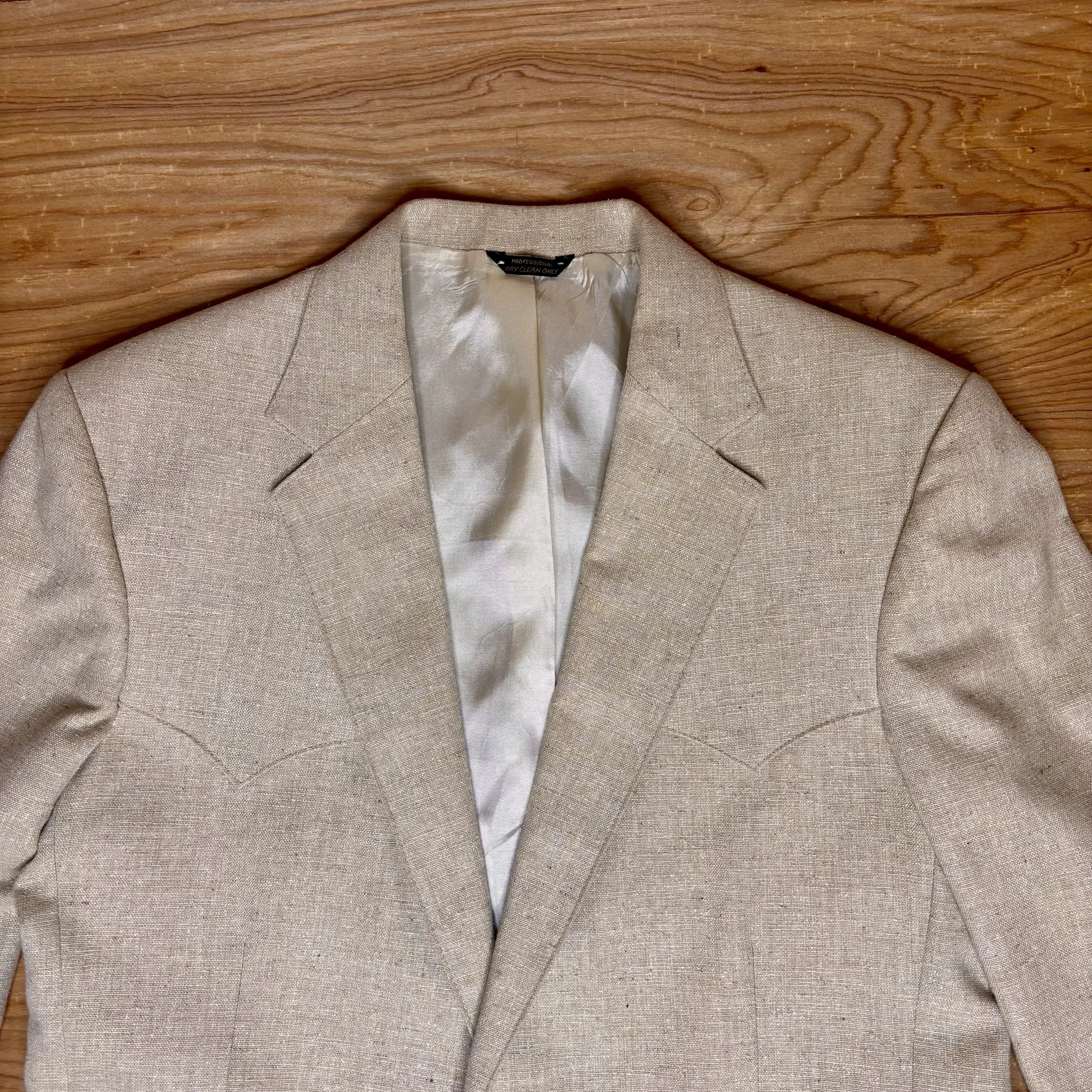 Close up Front view of vintage Levi's Western Wear blazer in beige linen-blend, showing tailored fit, curved Western yokes, and caramel-colored buttons.