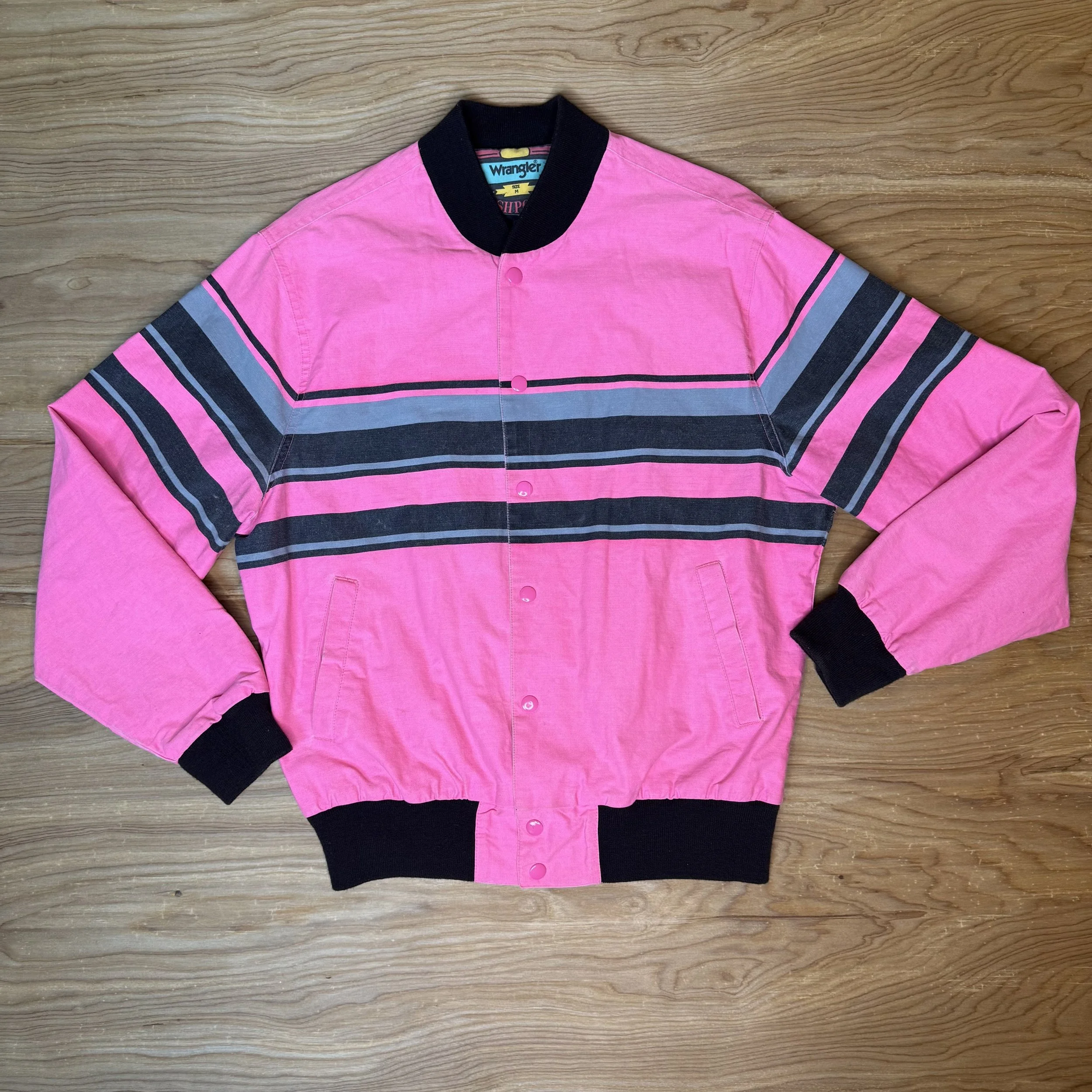 Front view of 1980s Wrangler Brushpopper bomber jacket in neon pink with slate and black horizontal stripes.