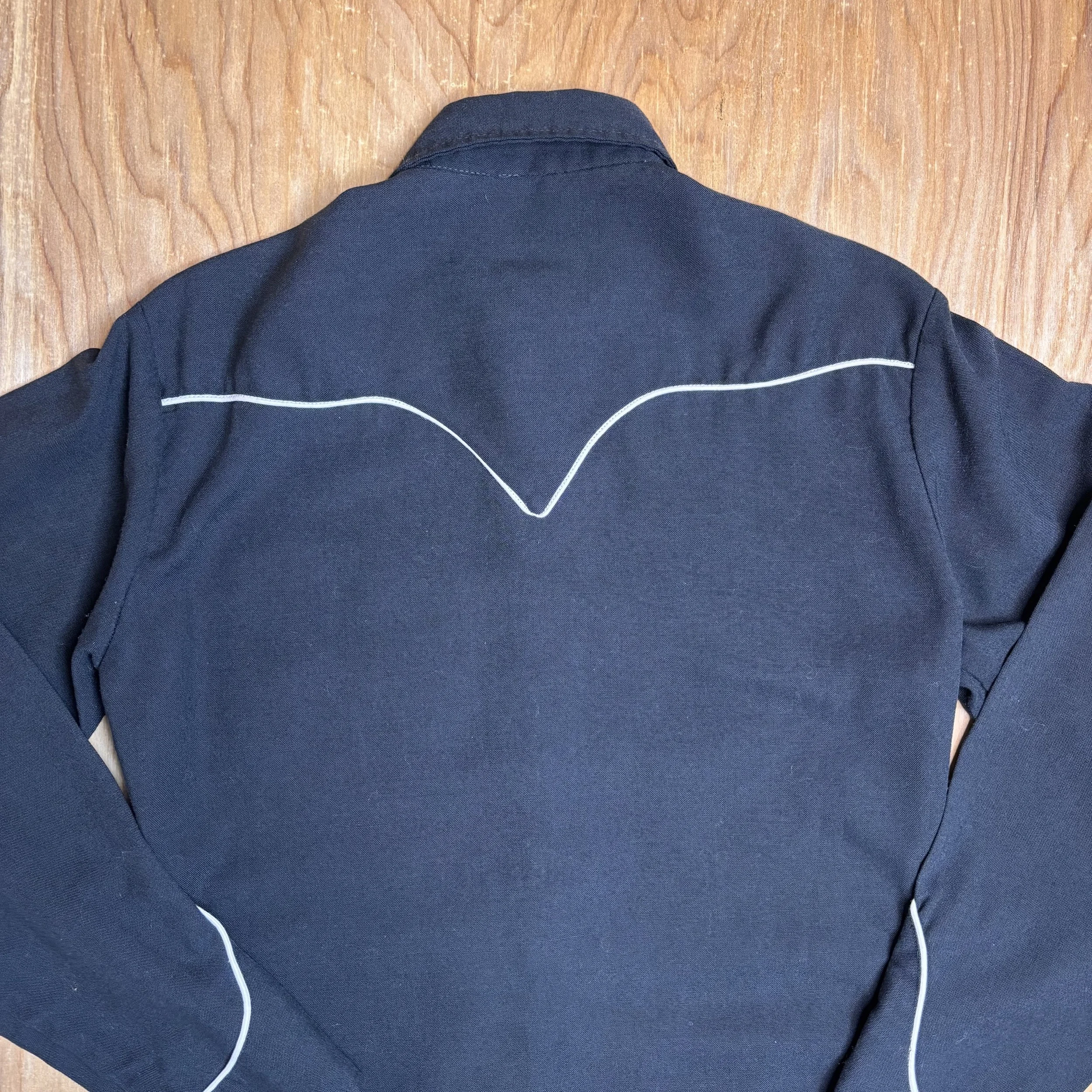 Close-up of back yoke piping detail on vintage black western pearl snap shirt.