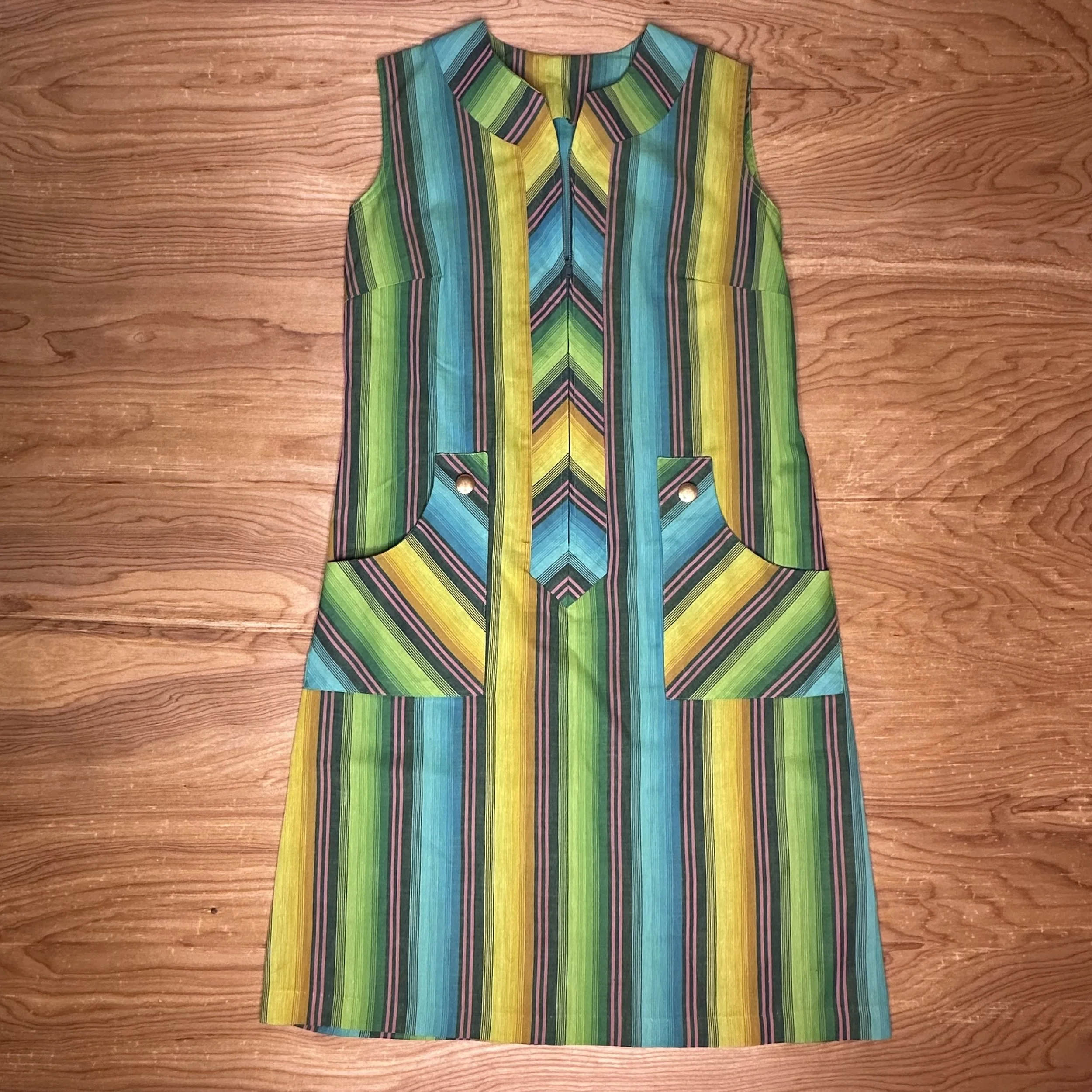 Front view of sleeveless 1960s mod dress with multicolor vertical and chevron stripes.