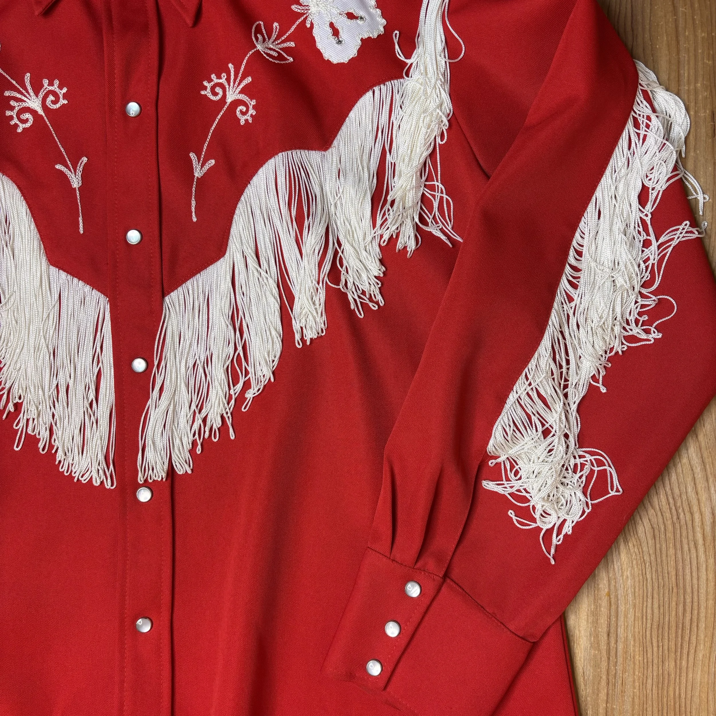 Side detail of sleeve showing fringe and cuff snap closures