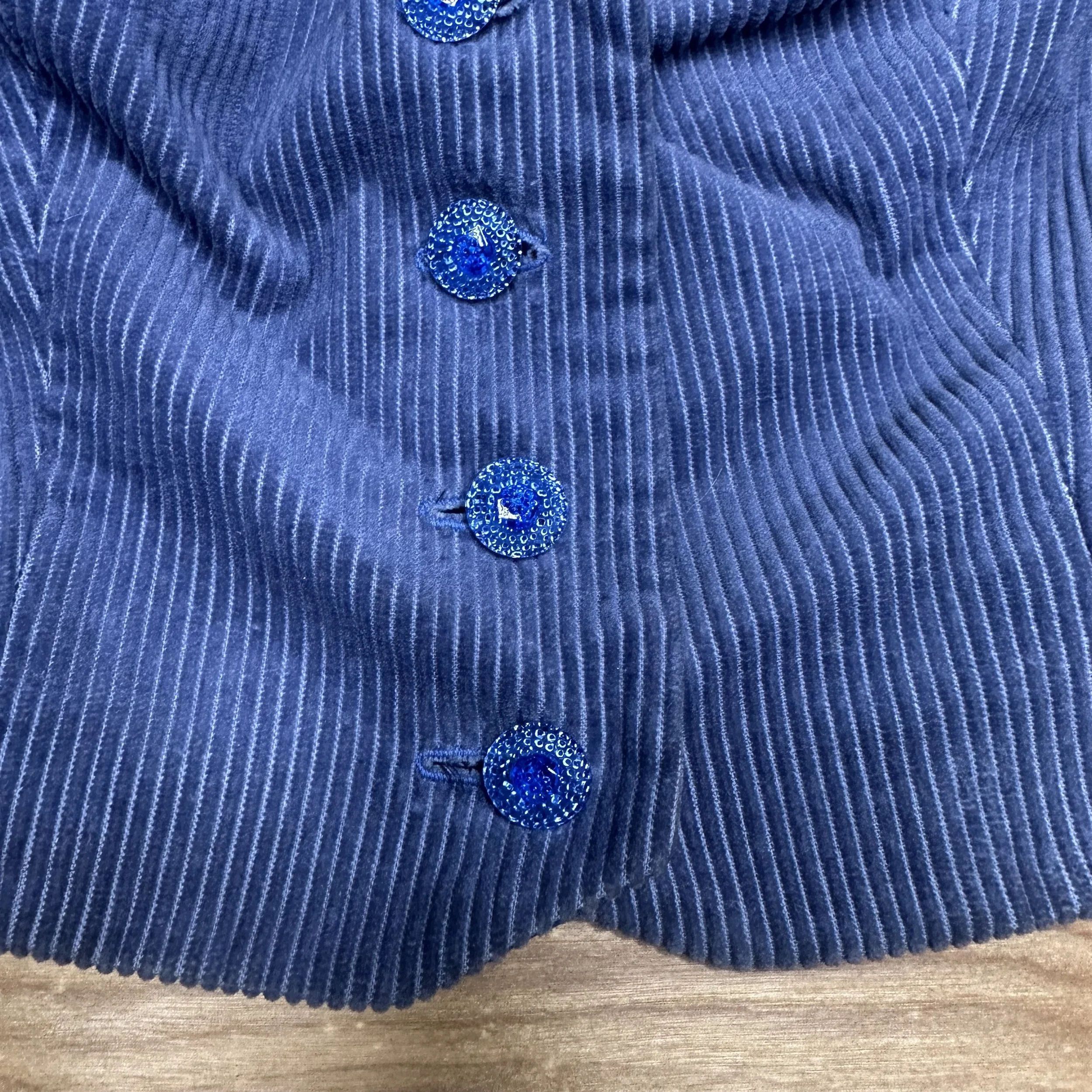Detail of the blue corduroy fabric and beaded buttons on the front of the vintage vest.