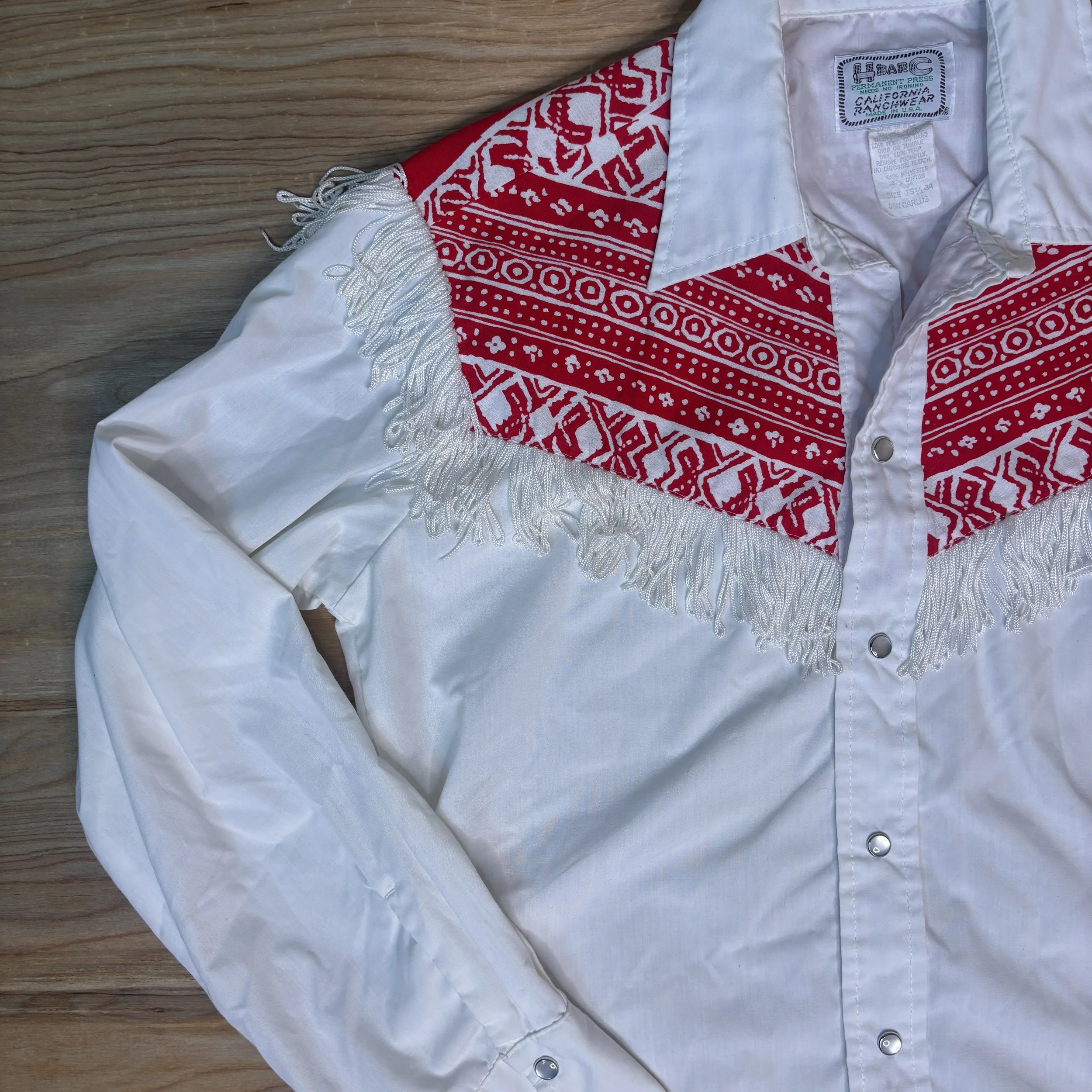 Detailed shot of red bandana print yoke and white fringe across chest on vintage H Bar C shirt.