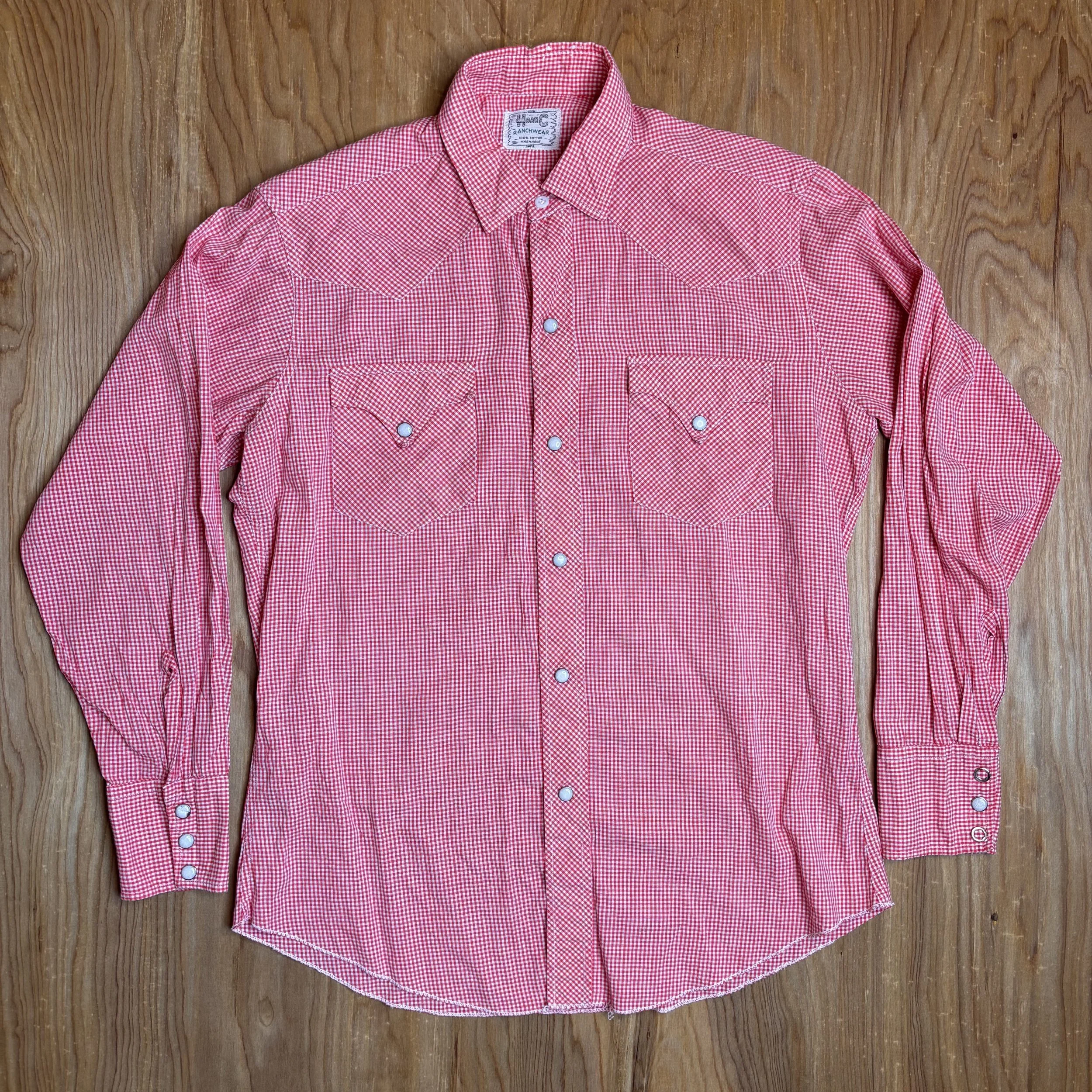Front view of vintage red gingham H Bar C pearl snap shirt laid flat