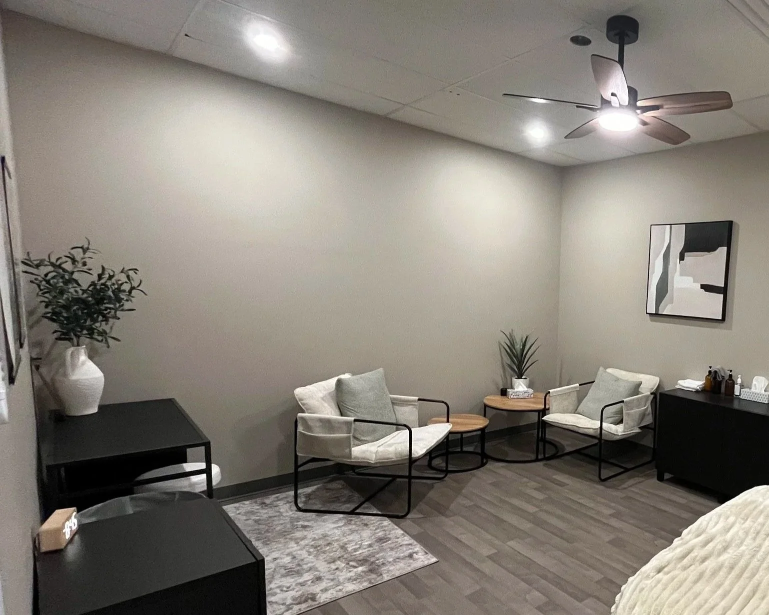 Person sitting on a dark gray couch with hands clasped and head bowed, in a dimly lit room.