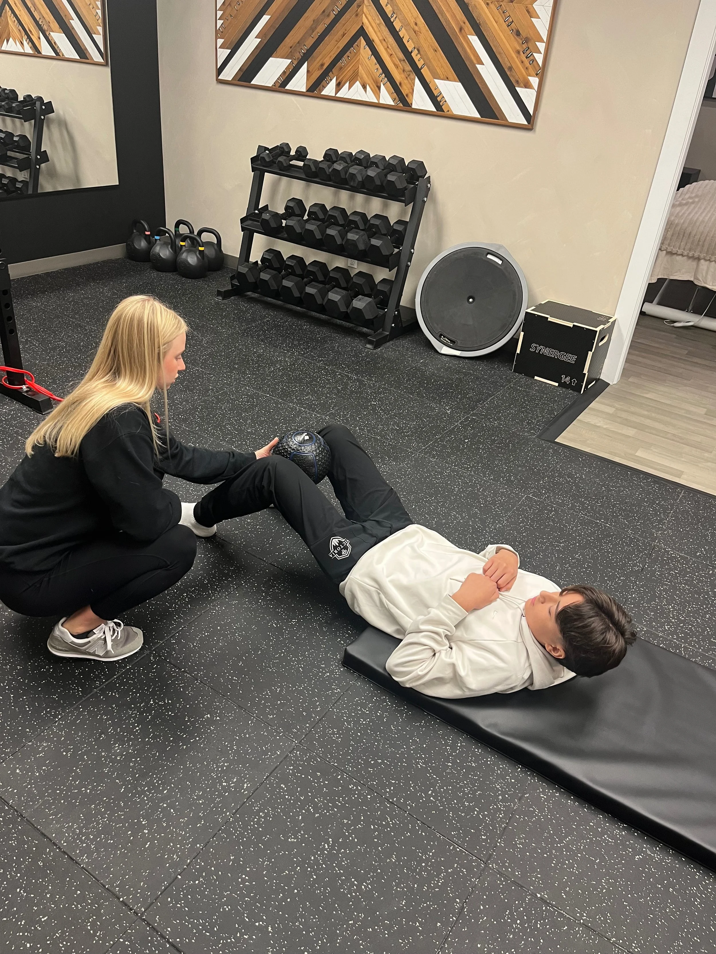 A person holding another person's arm with a green resistance band during a medical or therapy session.