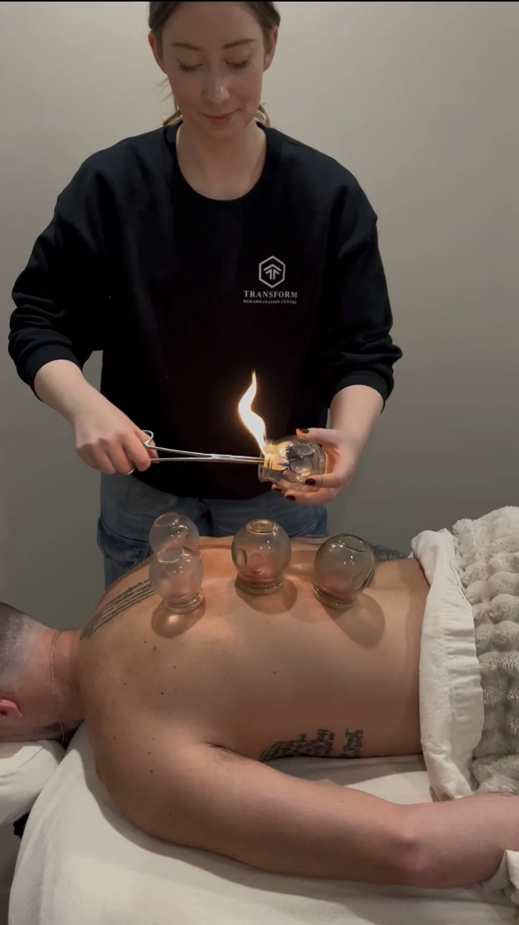 A person administering an injection into a patient's arm with a syringe, with another person's hands holding the patient's arm steady.