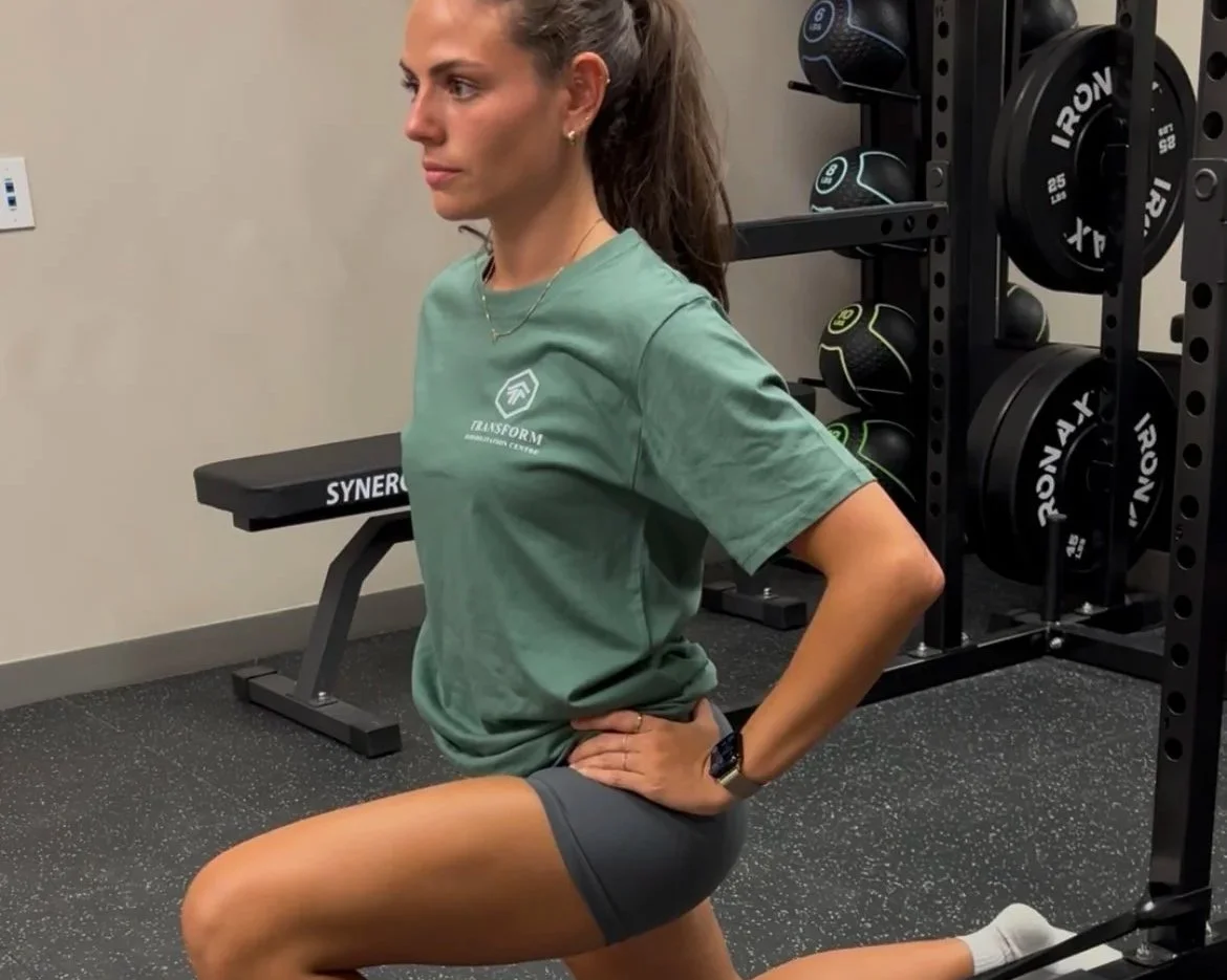 A woman holding a red foam roller during a physical therapy session.