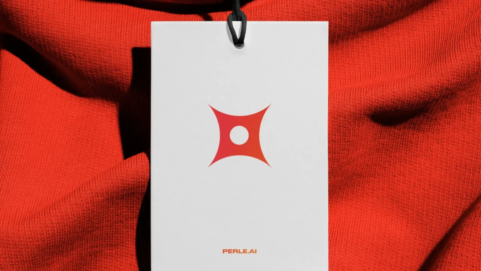 Close-up of a white tag with a red logo, attached to red fabric.