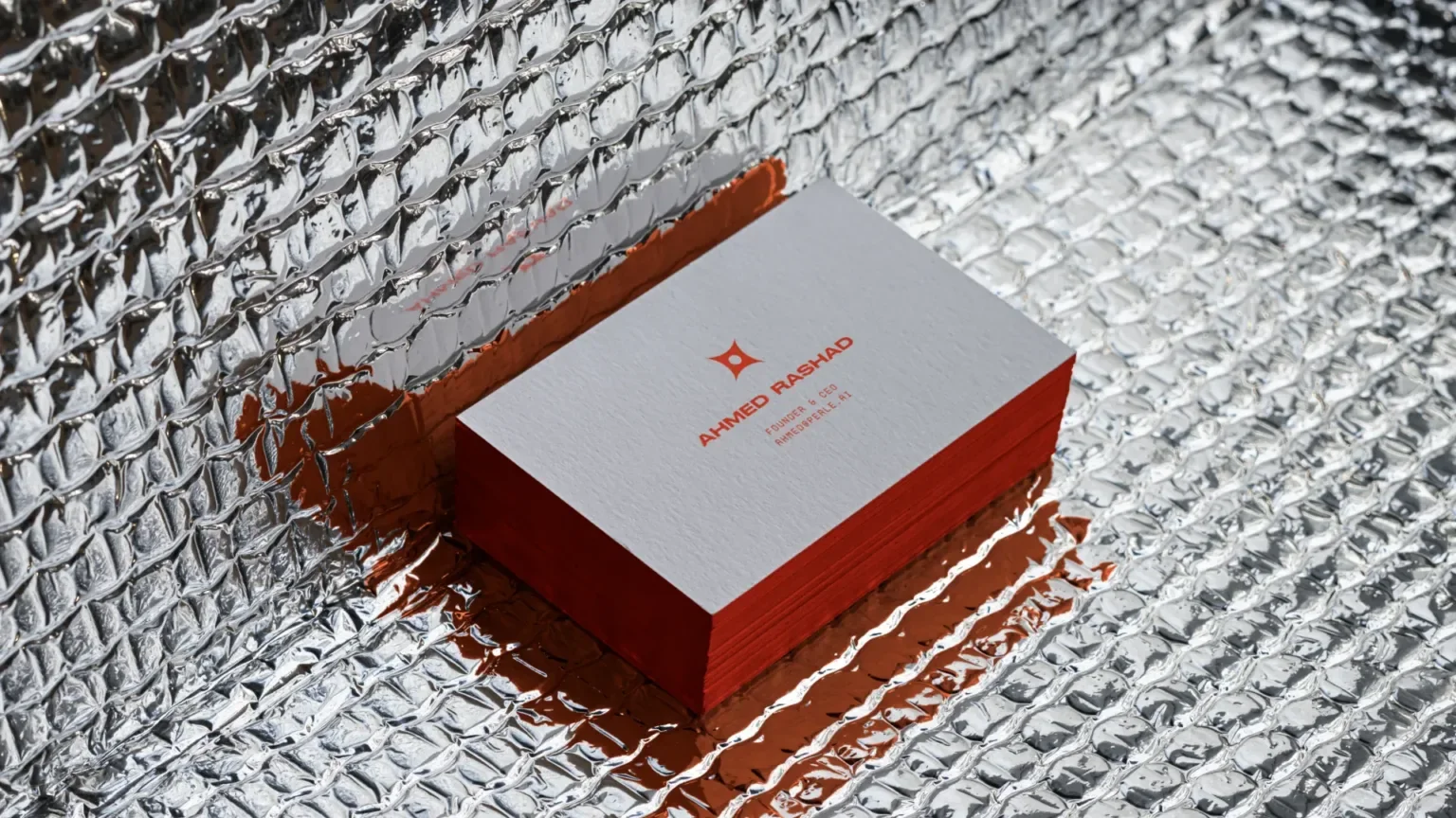 Stack of white business cards with red text and symbols on a reflective, metallic, textured surface.