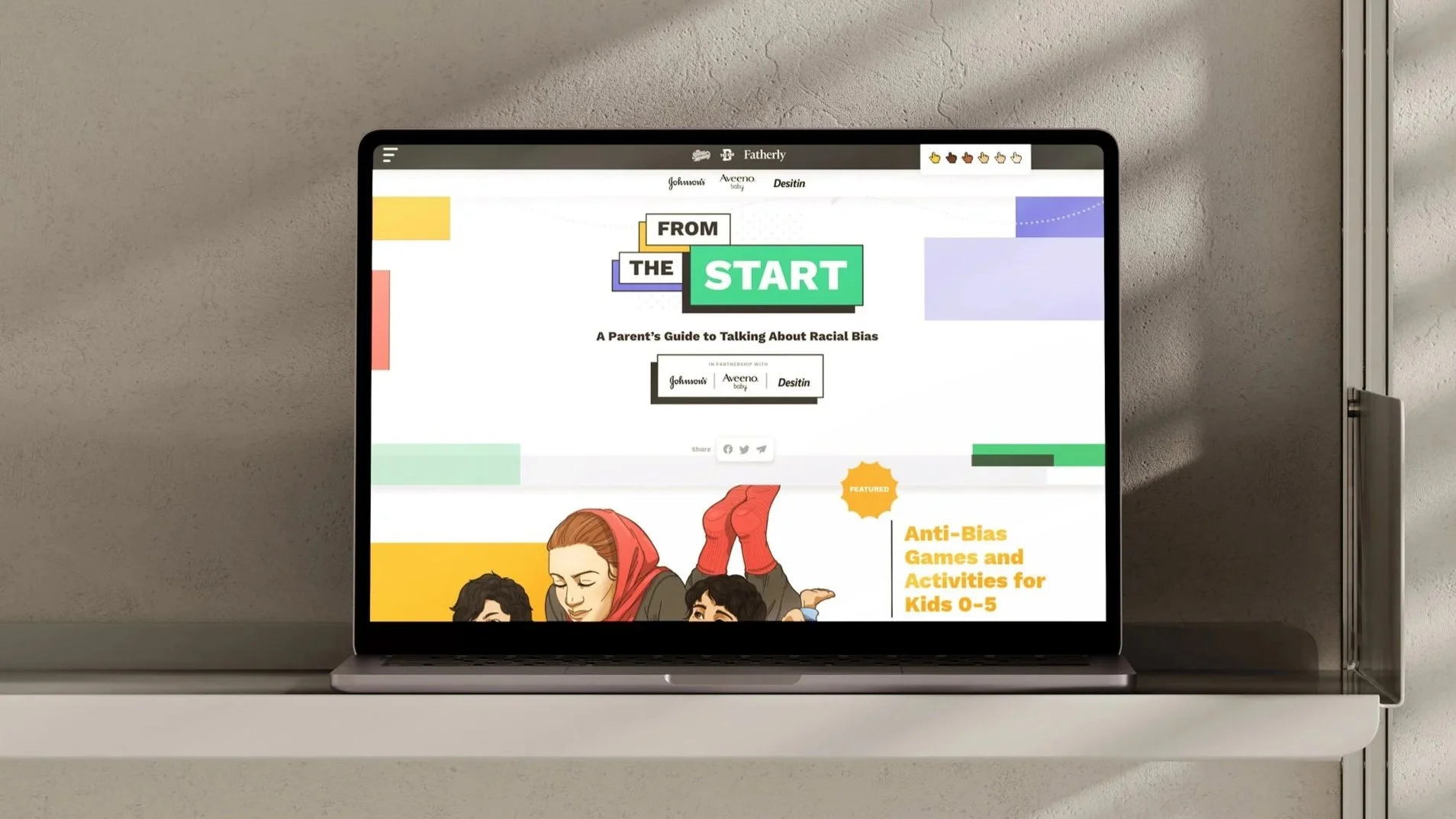 Laptop displaying a webpage titled "From the Start: A Parent's Guide to Talking About Racial Bias," with colorful graphics and illustrations of children and a woman, on a white desk against a gray textured wall.