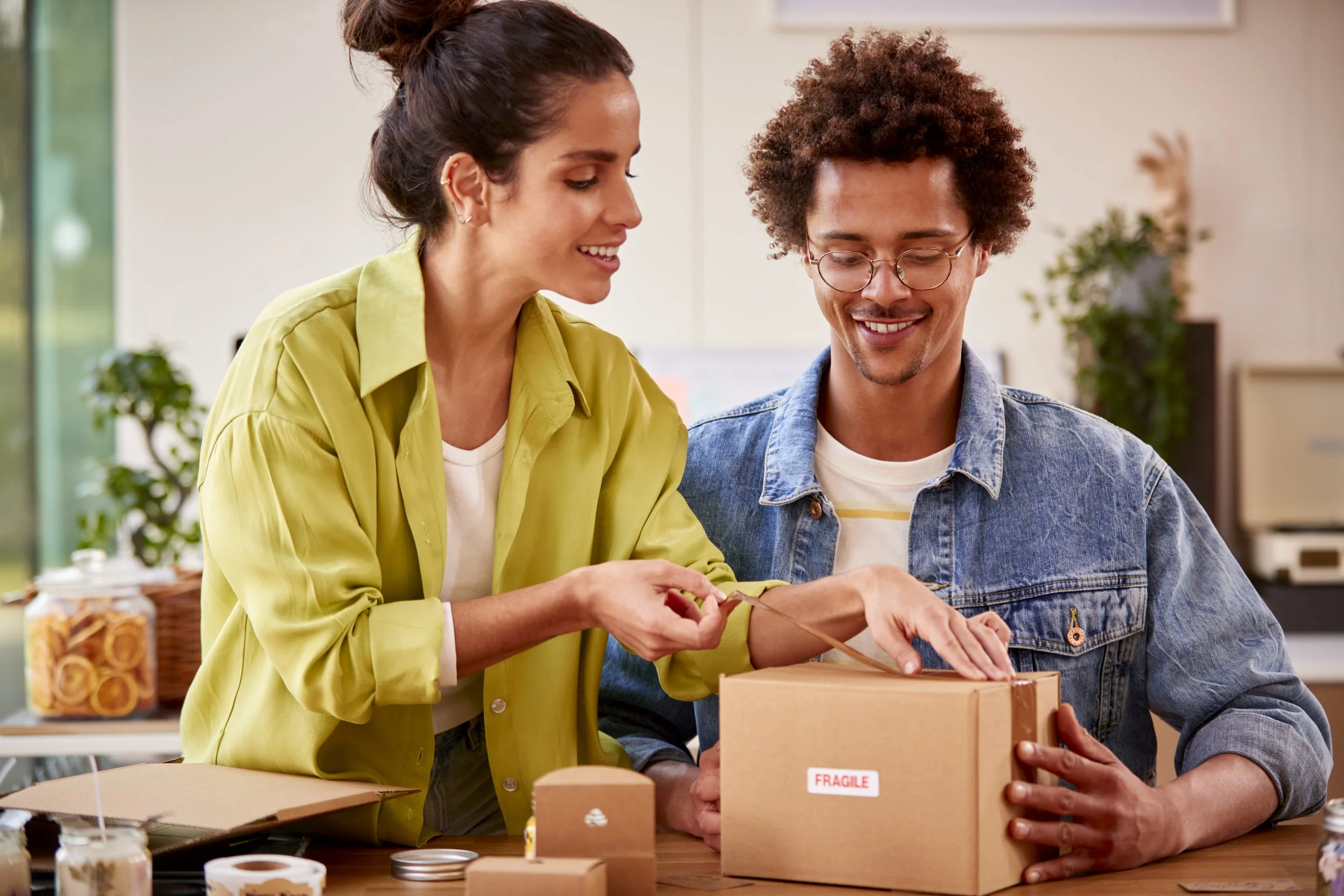 Two small business owners packing a branded product box, preparing an order for their Amazon stor