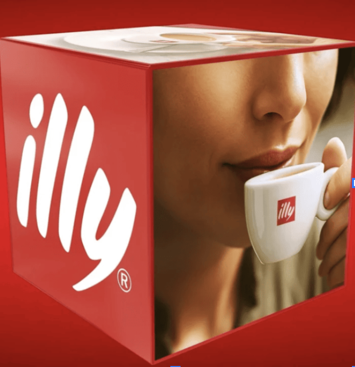 Red illy cube ad with the illy logo on one side and a close-up of a woman sipping from a white illy espresso cup on the other