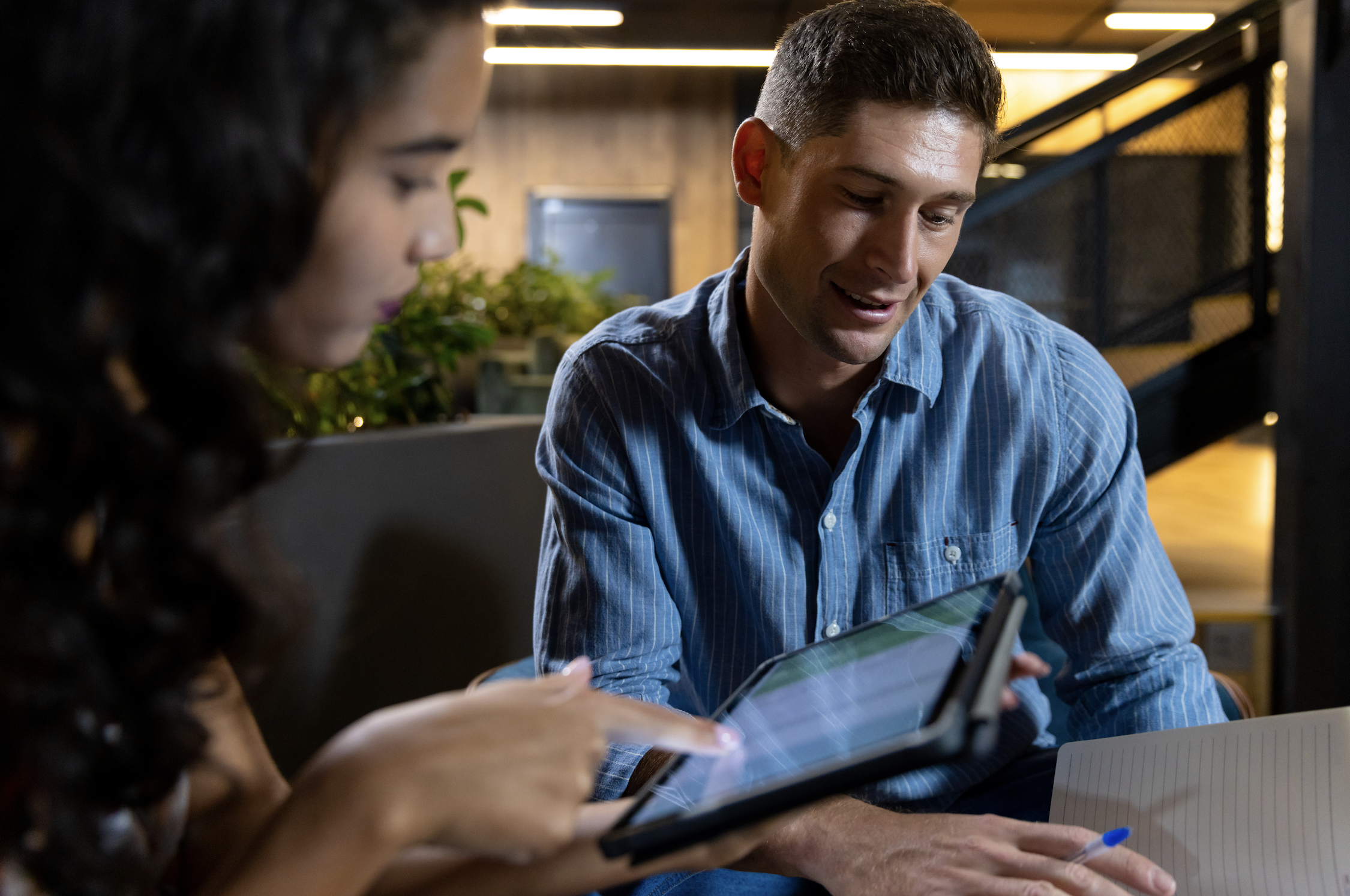 Two colleagues reviewing data on a tablet during a discussion.