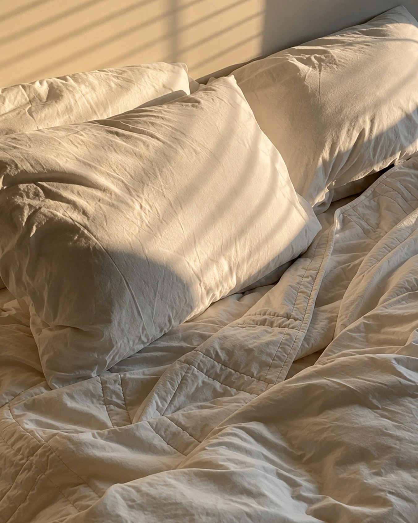 Baloo Living Co. bedding in soft morning light, pillows and a quilted blanket on the bed