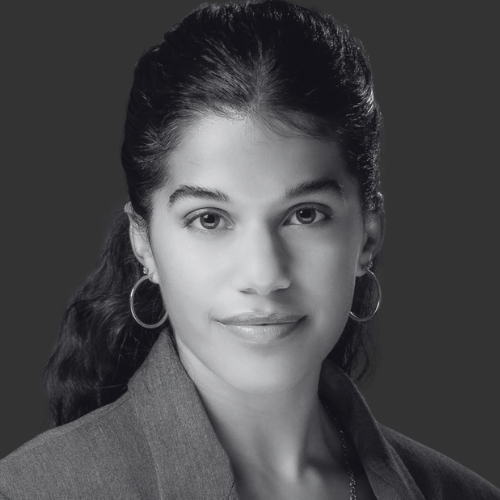 Black and white portrait of a woman with dark hair in a ponytail, wearing hoop earrings and a blazer, looking directly at the camera.