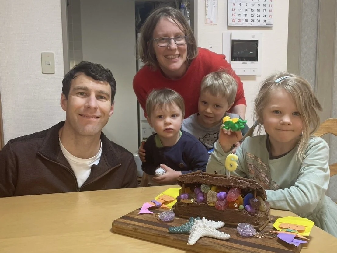 Family celebrating a birthday with a cake decorated with candy and toys.