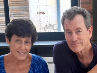 A woman and a man sitting next to each other indoors in front of a window.