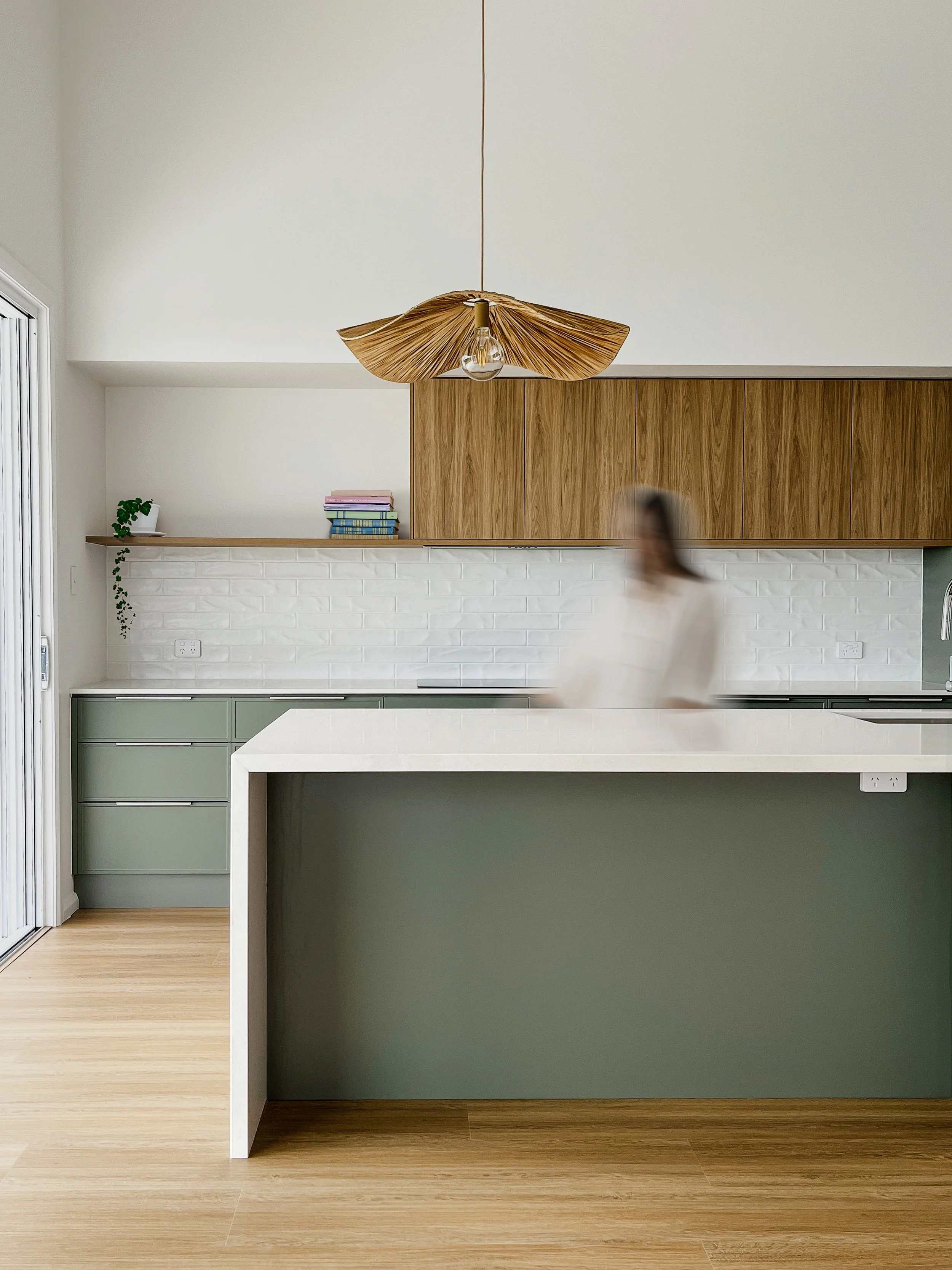 Modern coastl kitchen with sage green cabinets white tile backsplash and timber features